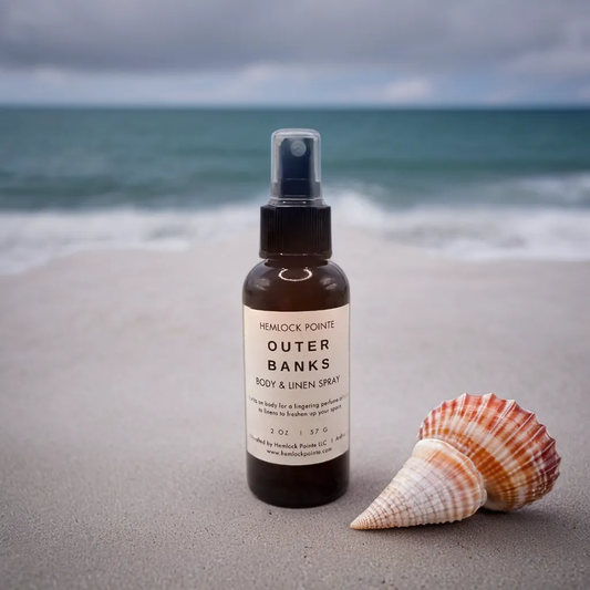 a bottle of hemlock pointe outer banks body and linen spray seashell in front of ocean